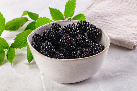 Raw sweet juicy blackberry in the bowl served leaves