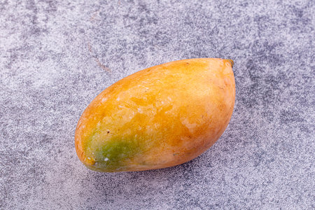 A fresh ripe mango with yellow, orange, and red skin on a rustic background. Still life for concepts...