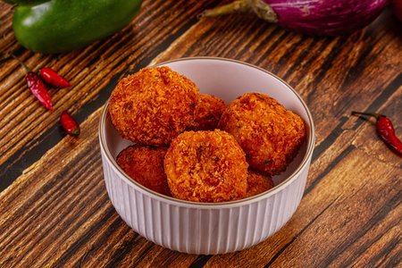 Top-down view of crispy golden-brown fried cheese and vegetable balls, a savory appetizer, on a...