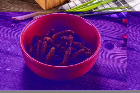 Appetizing still life of pickled gherkins in a grey bowl on a rustic wood table. This savory snack...