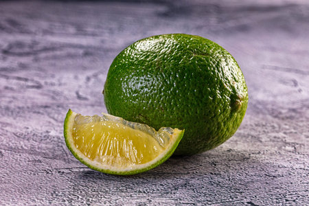 Close-up of a vibrant green lime and a sliced wedge, showing its juicy pulp. Still life food...