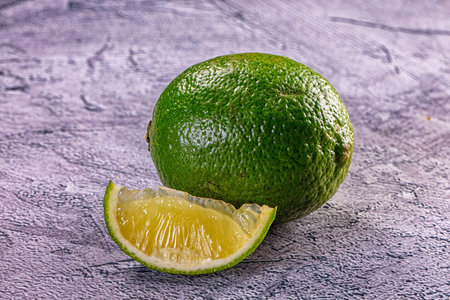 Close-up of a vibrant green lime and a sliced wedge, showing its juicy pulp. Still life food...