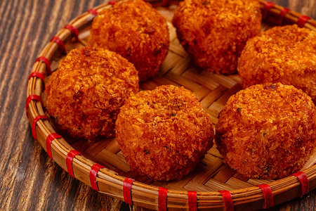 Top-down view of crispy golden-brown fried cheese and vegetable balls, a savory appetizer, on a...