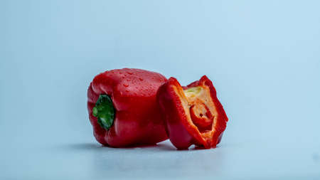 Fresh red bell pepper with chopped portion on blue gradient background in the left side of the frameの写真素材