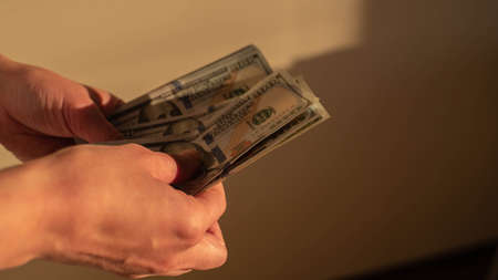White girl count US dollars in hands. Golden hour light