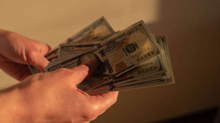 Girl hold many 100 dollars bills in her hands after salary. Nice golden light