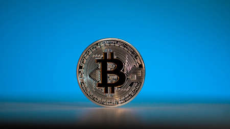 Silver coin of main cryptocoin in the world. Bitcoin with blue backgroundの写真素材