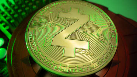 ZCASH gold coin and defocused chart background. Virtual cryptocurrency concept. Green light on the isolated backgroundの写真素材