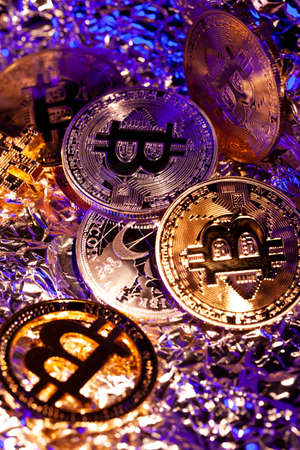 Many gold coins Bitcoin with blue and yellow light. Many nice reflections. Close-up shotの写真素材