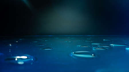 Condensation water drops on black glass background. Rain droplets with light reflection on dark window surface, abstract wet texture, scattered pure aqua blobs patternの写真素材