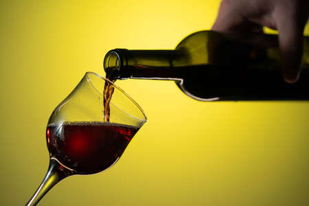 red wine is poured from a bottle into a glass. Nice close up shotの写真素材