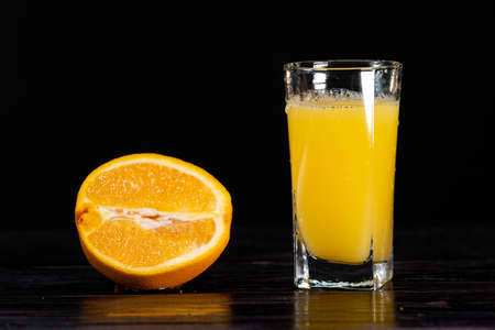 A ripe sliced orange and a tall glass of juice on a wooden background. close-up. healthy lifestyle. healthy eating. vitaminsの写真素材