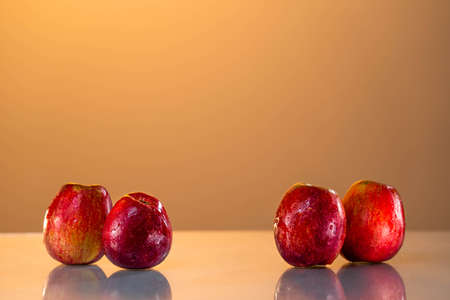 Red apples are on the table. reflective surface, yellow background. sunset. summer mood. nice weather. healthy lifestyle. vitaminsの写真素材