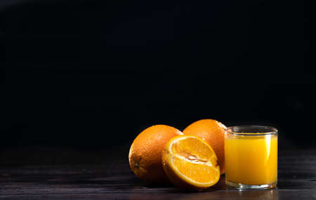 glass of fresh orange juice and oranges on a vintage wooden background. For the design signitureの写真素材