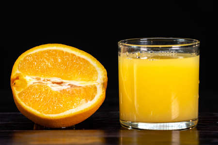 A ripe sliced orange and a glass of juice on a wooden background. close-up. healthy lifestyle. healthy eating. vitaminsの写真素材