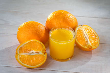 Orange juce, half of orange on the wooden white table. Summer mood. close up shot. raw footageの写真素材