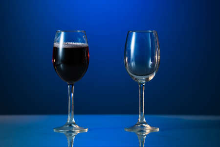 Red wine glass and white wine glass isolated on a blue backgroundの写真素材