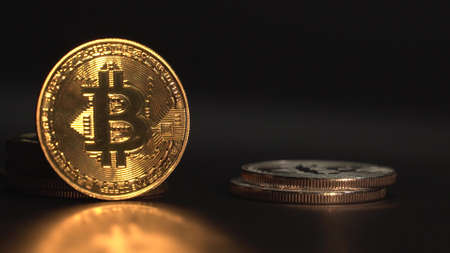 Golden Bitcoin BTC with reflection on the glass. Many oher crypto coins appea one after another in frame Black background.の写真素材