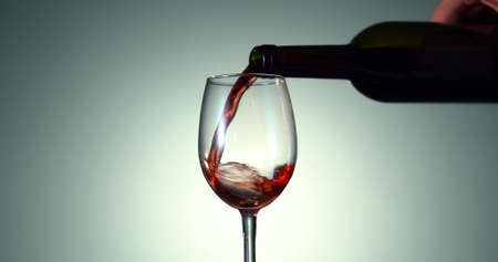 Pouring Rose Wine from a Transparent Bottle into the glass on the White Background. Alcohol conceptの写真素材