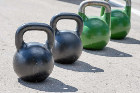 black and green weights are standing on the pavementの写真素材