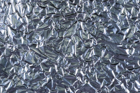 background of crumpled glossy metallic foil closeupの写真素材