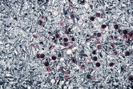 background of crumpled glossy metallic foil and rhinestones closeupの写真素材