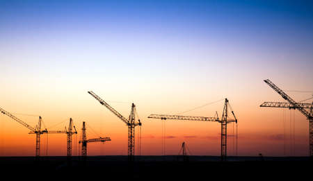 Cranes on a construction site against a sunset skyの写真素材