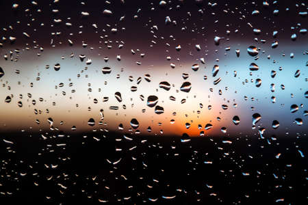 Abstract water rain drops on window glass after rain during sunsetの写真素材