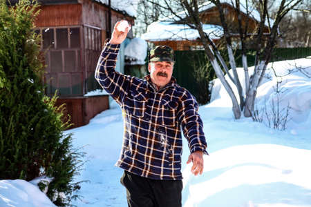Senior man playing snow outdoors in sunny winter  dayの写真素材