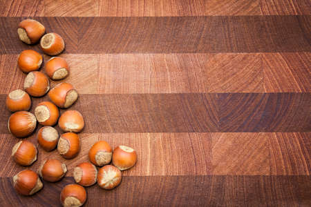 Wooden  surface  with hazelnuts and copy space. Handful of hazelnuts disposed from left side. Right side can be used for textの写真素材