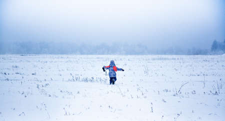 Happy girl playing and running in a snowy winter park in winter dayの写真素材
