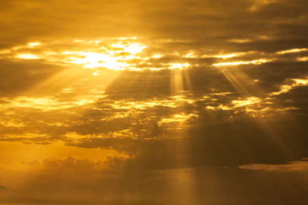 orange sunset sky with light rays going through cloudsの写真素材