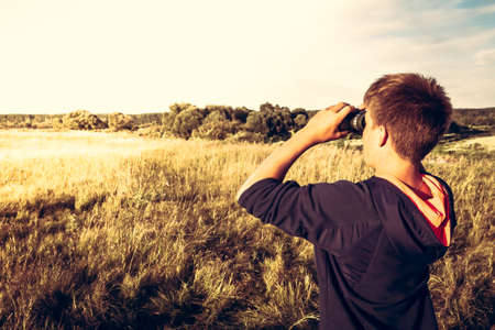 Young boy with binoculars in a wheat field looking into the distance. concept for future, discovery,...