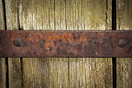 Old rusty metal plate with copy space on weathered wooden surfaceの写真素材