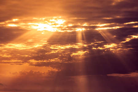 Beautiful orange sunset sky with light rays going through cloudsの写真素材