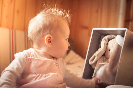 Baby girl playing with plush rabbit received as a giftの写真素材