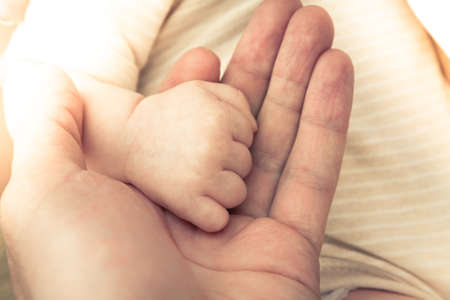 Father holding his newborn baby hand symbolizing love and care.