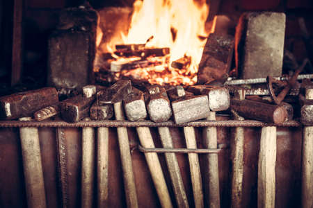 Blacksmith shop with hammers and burning furnace on background