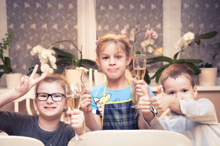 children toasting with juice in festive glass at children partyの写真素材