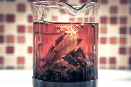 Herbal tea with leaves and flowers in transparent cupの写真素材