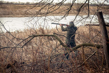 Hunter man with gun aiming and prepared to make a shot during huntの写真素材