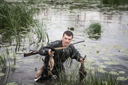 hunter man with prey after a successful hunt break through marshland