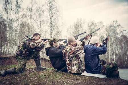 group of people with guns aimed to the sky and prepared to make a shotの写真素材