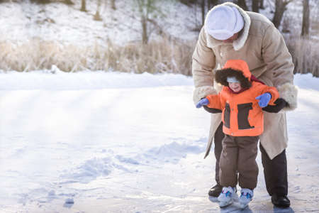 Family enjoying ice skating on outdoors skating rink in a snowy park during winter holidaysの写真素材