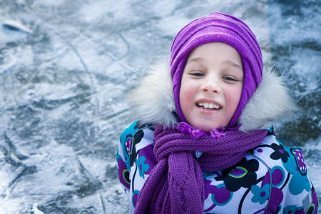 Child sitting on ice after falling in snowy park during winter holidays with copy spaceの写真素材