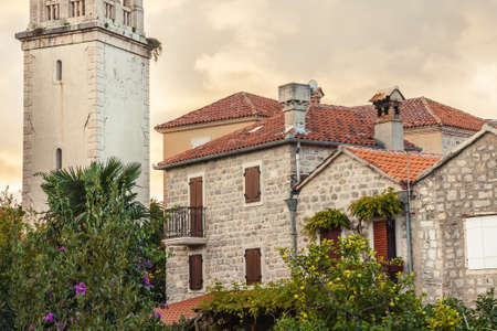 Old historical building facade with orange roof tiles in retro vintage style during sunset in old European townの写真素材