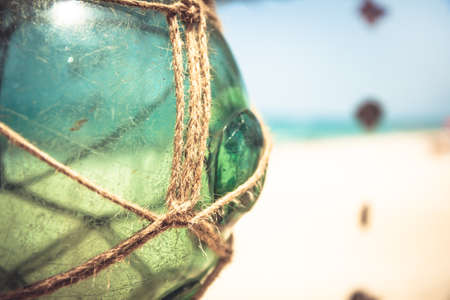 Empty vintage glass jar with rope on tropical beach with blurred background and copy spaceの写真素材