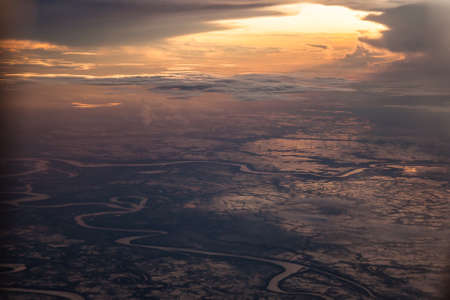 Sunrise over the earth. Sunlight breaks through the clouds and illuminates the earth by first rays of the sun.の写真素材