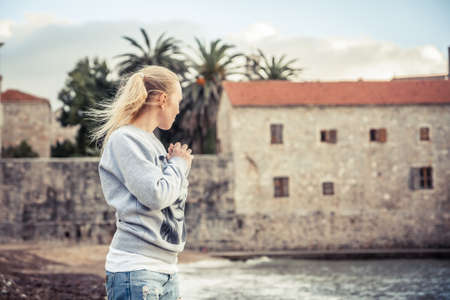 Pensive lonely woman standing on beach and looking into the distance wind blowing woman hairsの写真素材