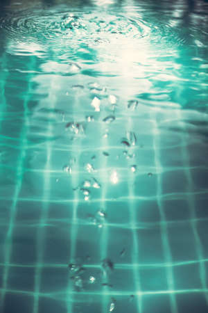 Swimming pool water surface with bubbles and ripples in transparent turquoise water with net pattern in vintage styleの写真素材